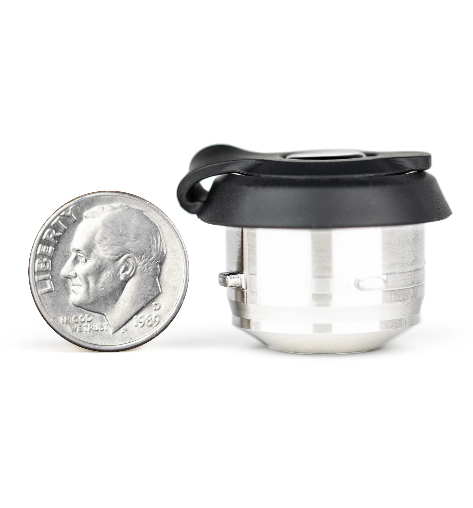 A silver coin next to a small metal object, which appears to be a camera lens or a small metal container.