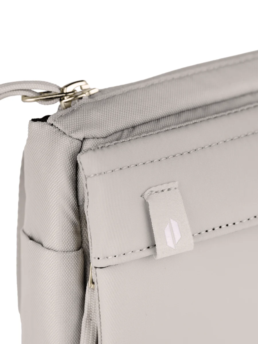 A close-up view of a gray fabric bag with a zipper closure and a small white logo on the front.