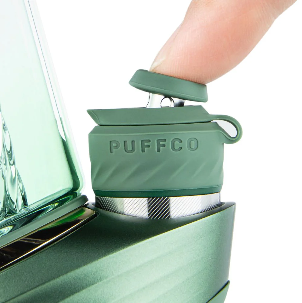 A close-up view of a green electronic device, possibly a blender or mixer, with a person's finger partially visible on the right side.