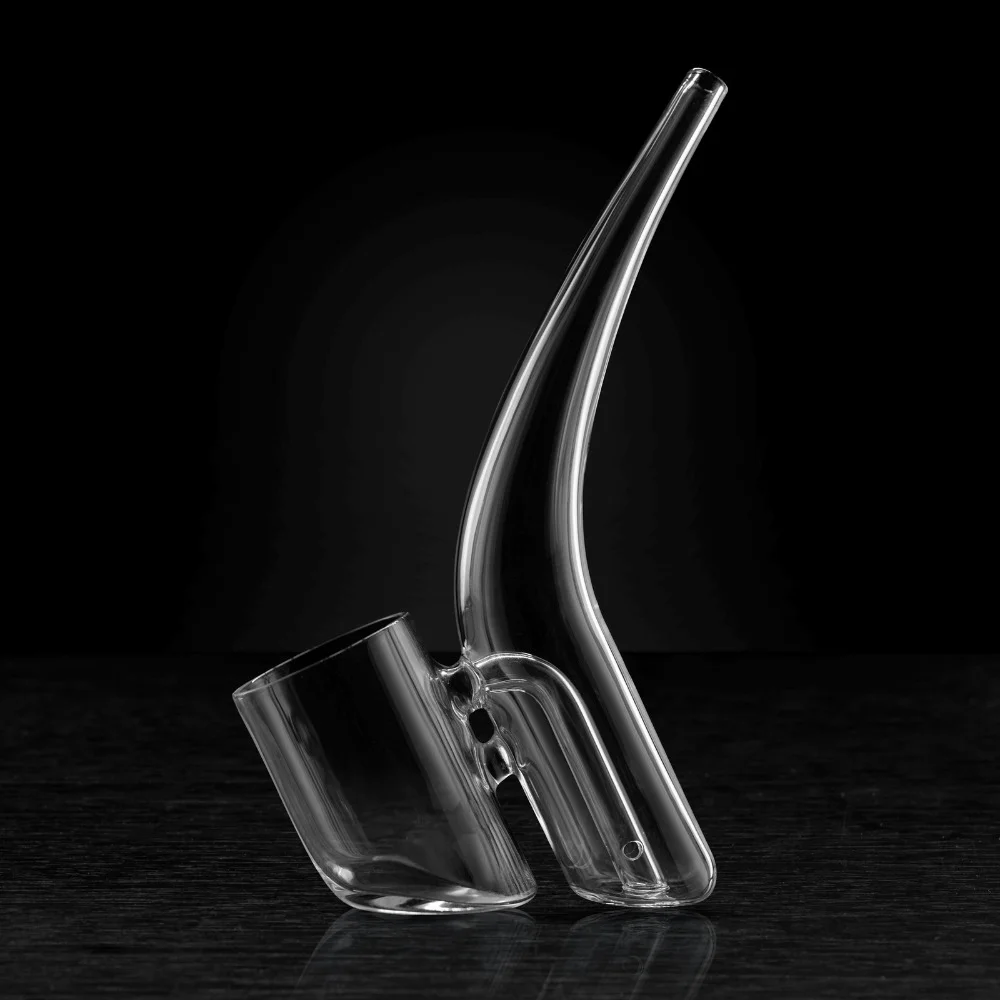 A clear glass pipe with a handle, positioned on a dark surface against a black background.