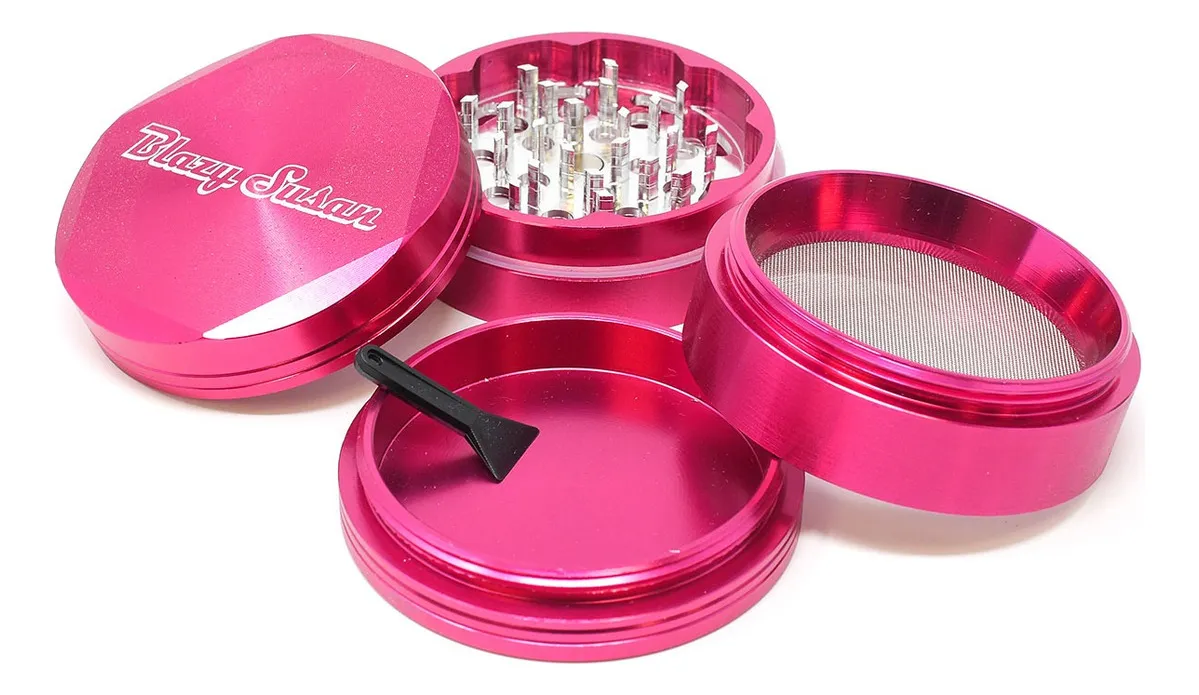 A pink metal grinder with a mesh screen, and a black tool inside the grinder.