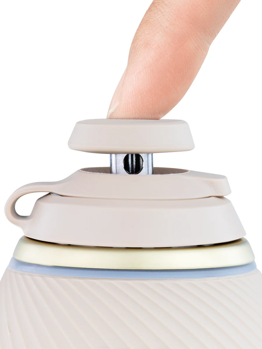 A person's finger is shown adjusting a beige object with a silver latch, which appears to be a small, round device with a handle.
