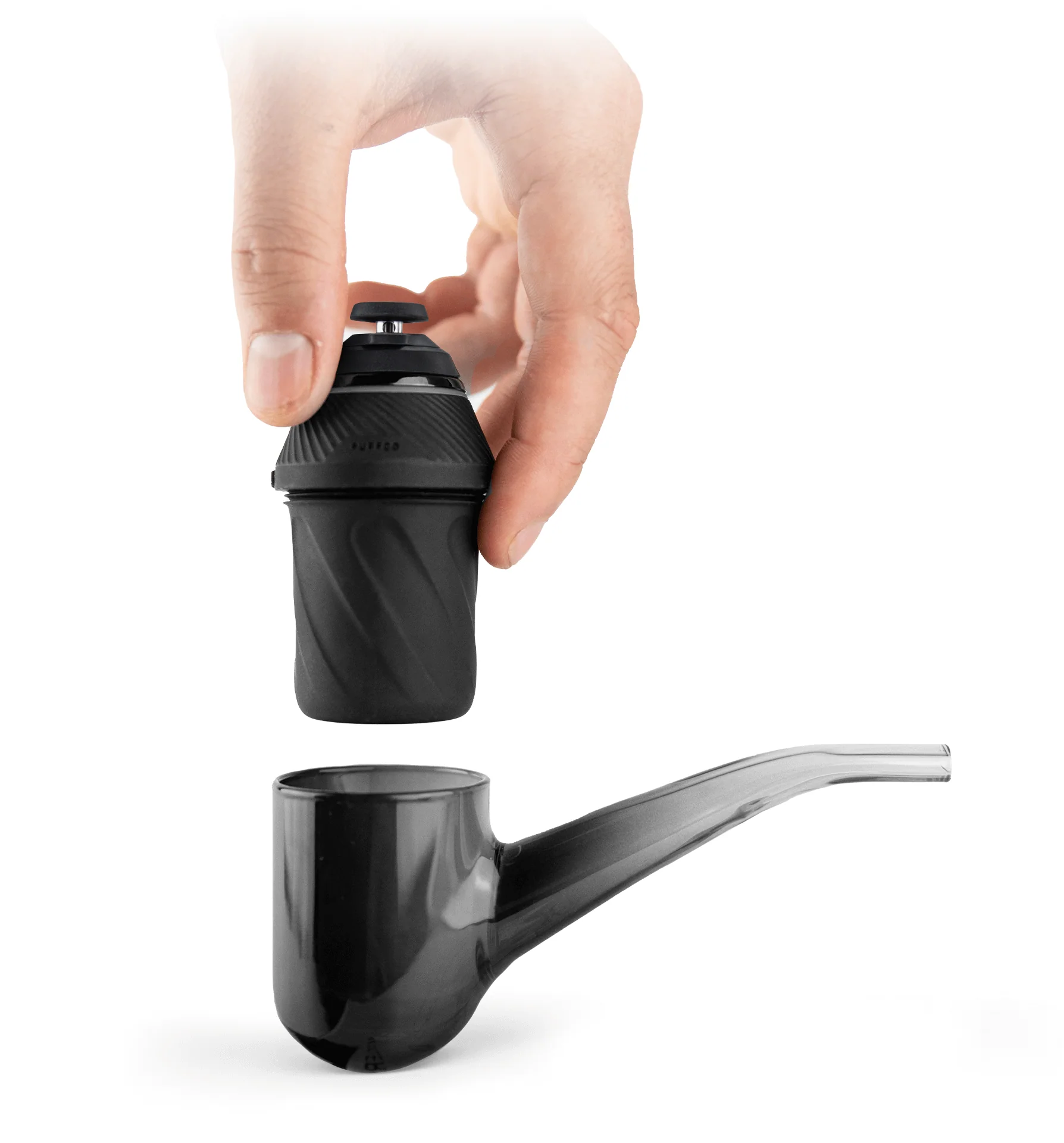 A hand is holding a black object, which appears to be a small black container or device, and is placing it into a transparent glass container or pipe.