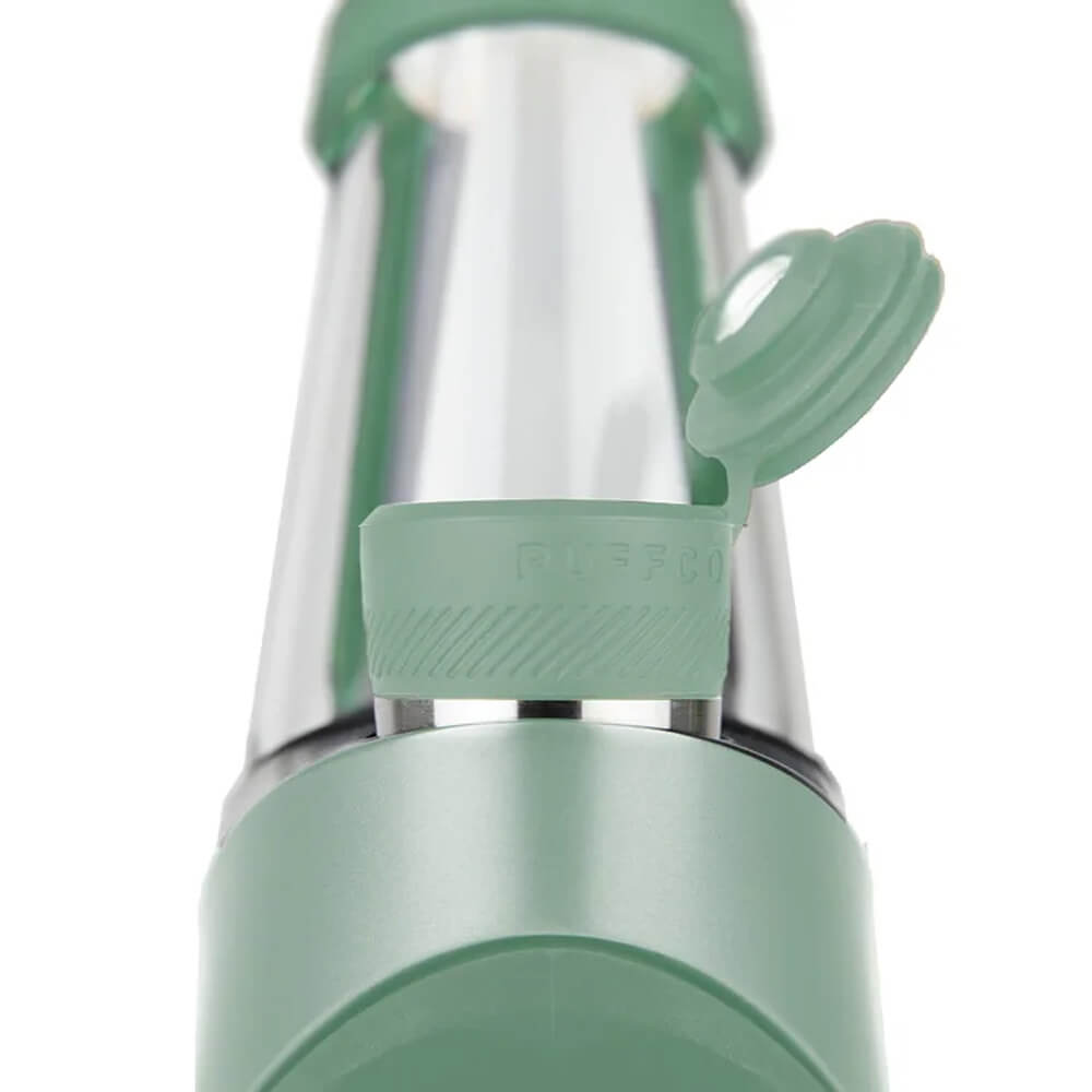 A close-up view of a green and silver object, possibly a container or tool, with a lid or cap on top.