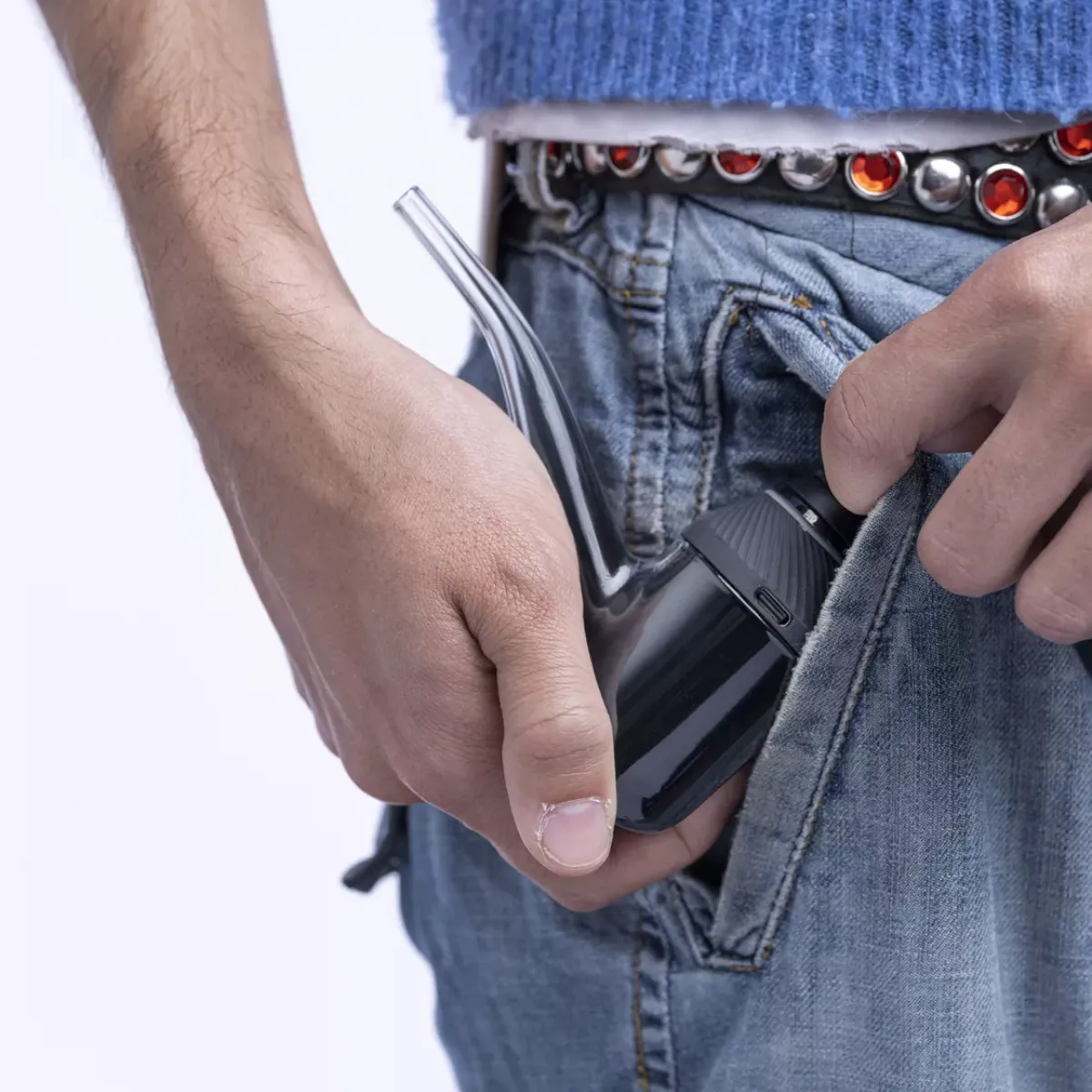 A person's hand holding a black electronic device, possibly a phone or tablet, in their pocket.
