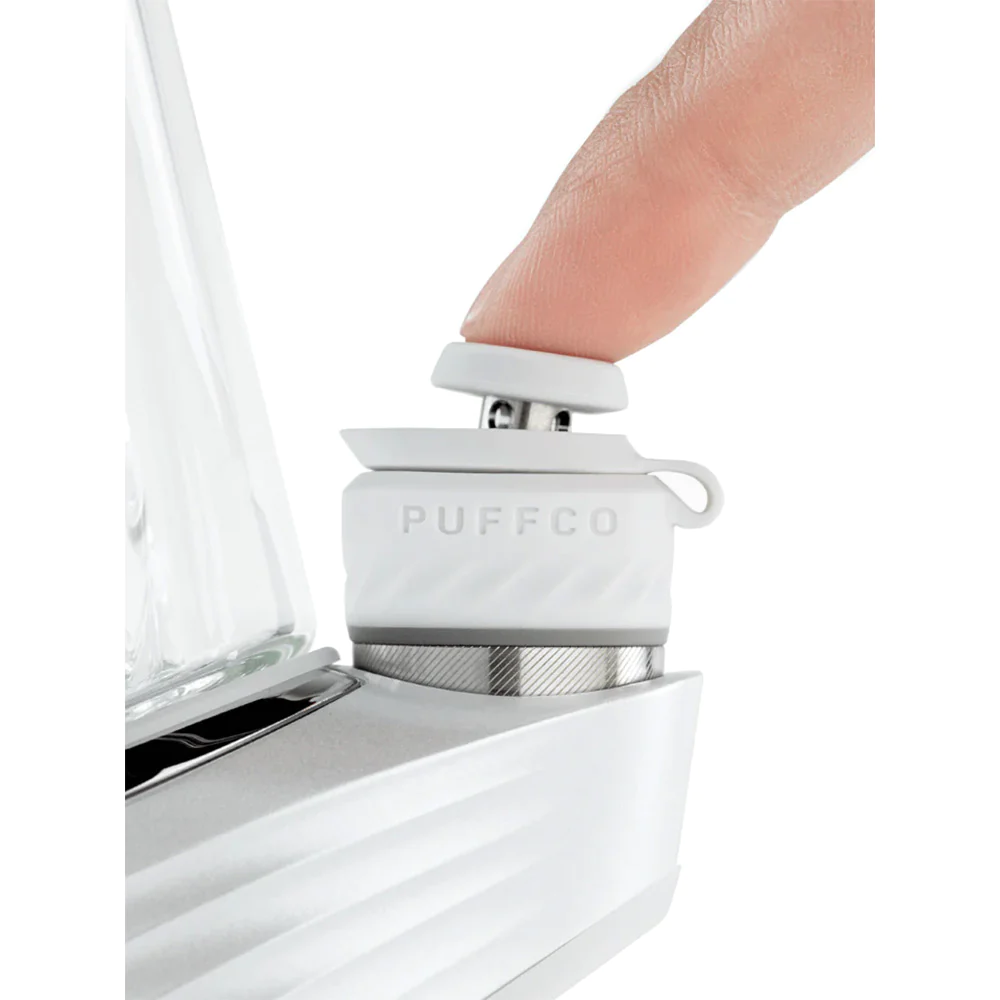 A person's finger is shown interacting with a white electronic device, which appears to be a small white device with a silver base.