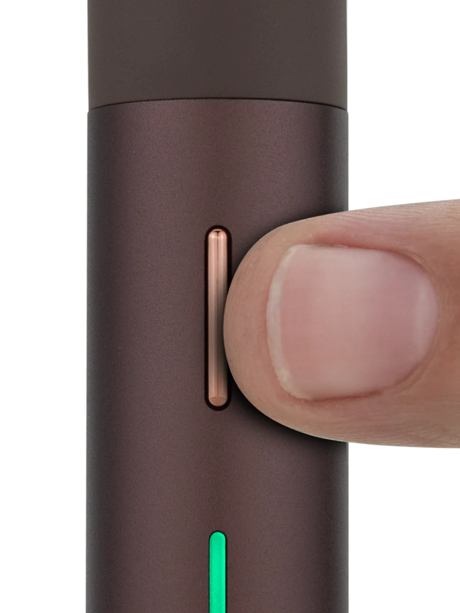 A close-up view of a thumb pressing a button on a dark brown object, which appears to be a small electronic device.
