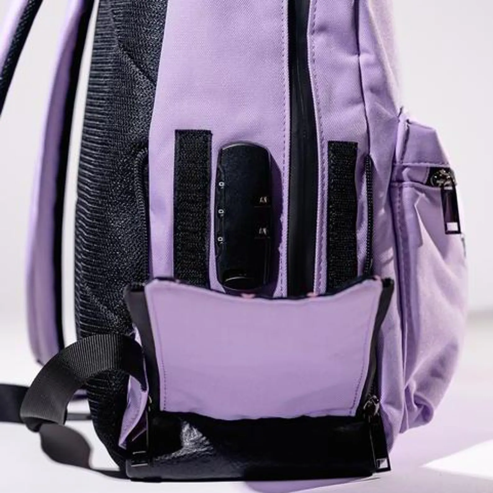 A purple backpack with a black zipper and a black lock attached to it.