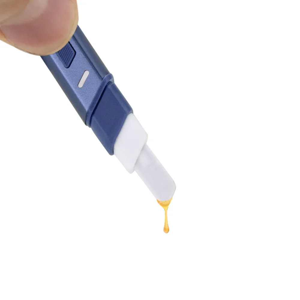 A blue and white electronic device is being used to transfer a yellow liquid, possibly a syrup or lotion, from one container to another.