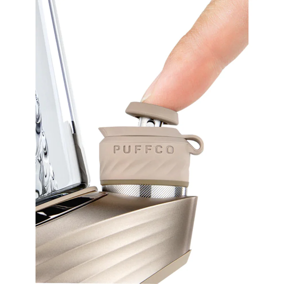 A person's thumb is shown interacting with a device, which appears to be a small, beige-colored object with the word "PUFFCO" printed on it.