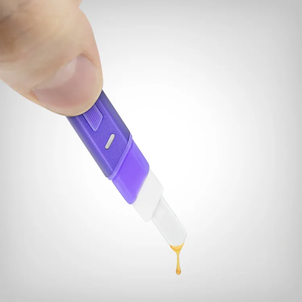 A hand is holding a purple and white object, which appears to be a small, handheld device, and there is a drop of liquid coming out of it.
