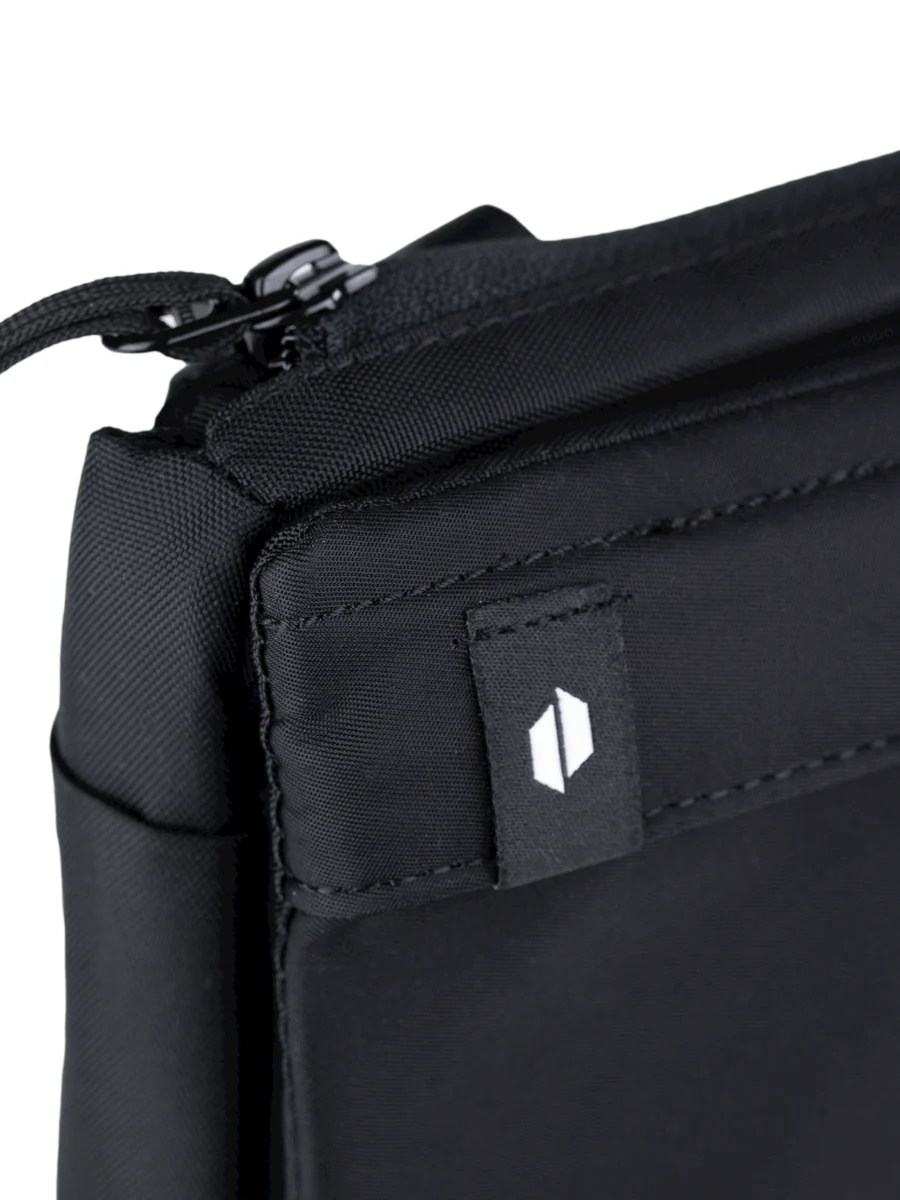 A close-up view of a black bag with a zipper closure and a small logo on the front.
