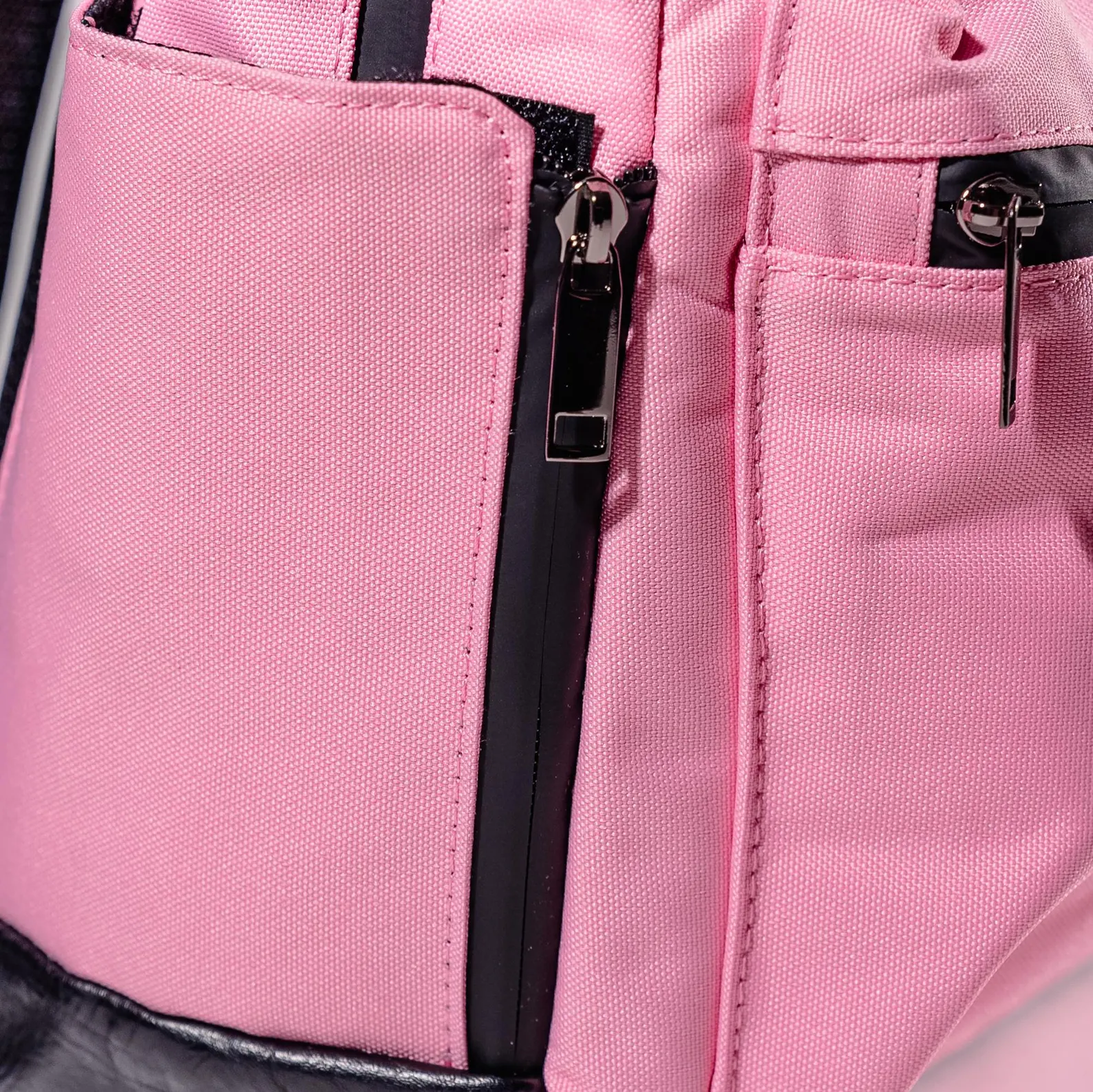 A close-up view of a pink fabric pocket on a bag, with a zipper visible.