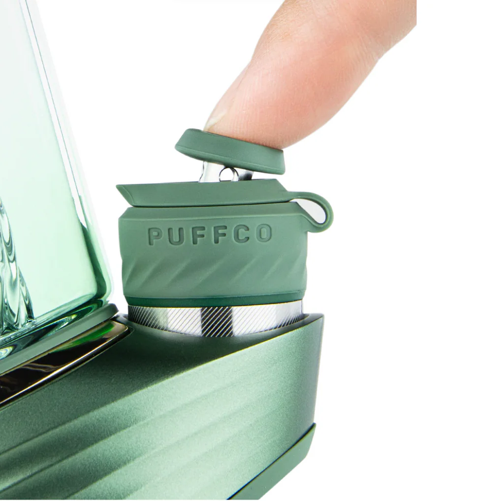A person's hand is shown interacting with a green object, which appears to be a device or appliance, with the word "PUFFCO" visible on it.